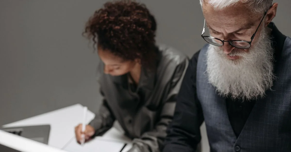 Dos profesionales trabajando colaborativamente en un escritorio en un entorno de oficina.